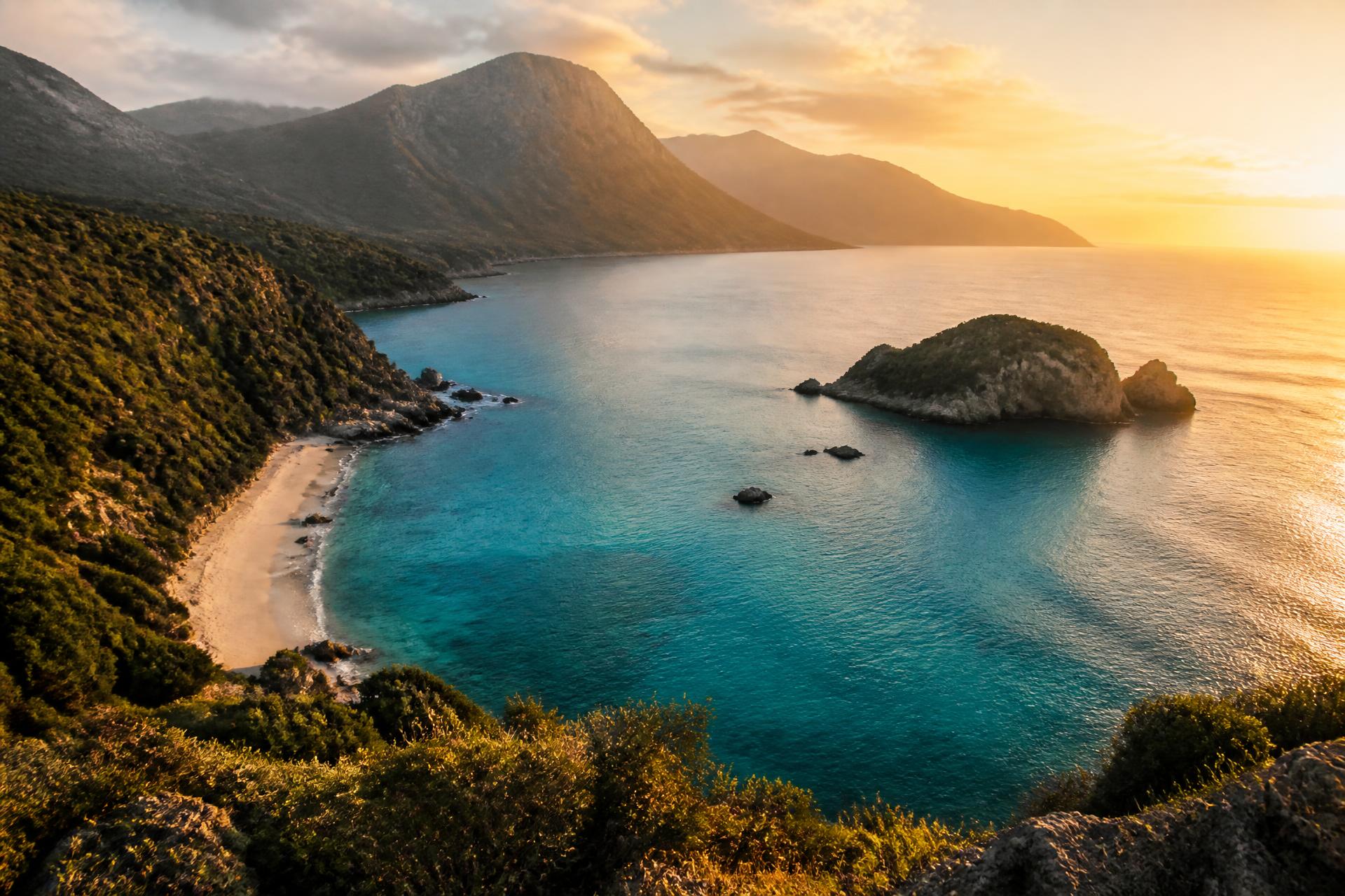 Turquoise coastal bay framed by green cliffs at golden hour